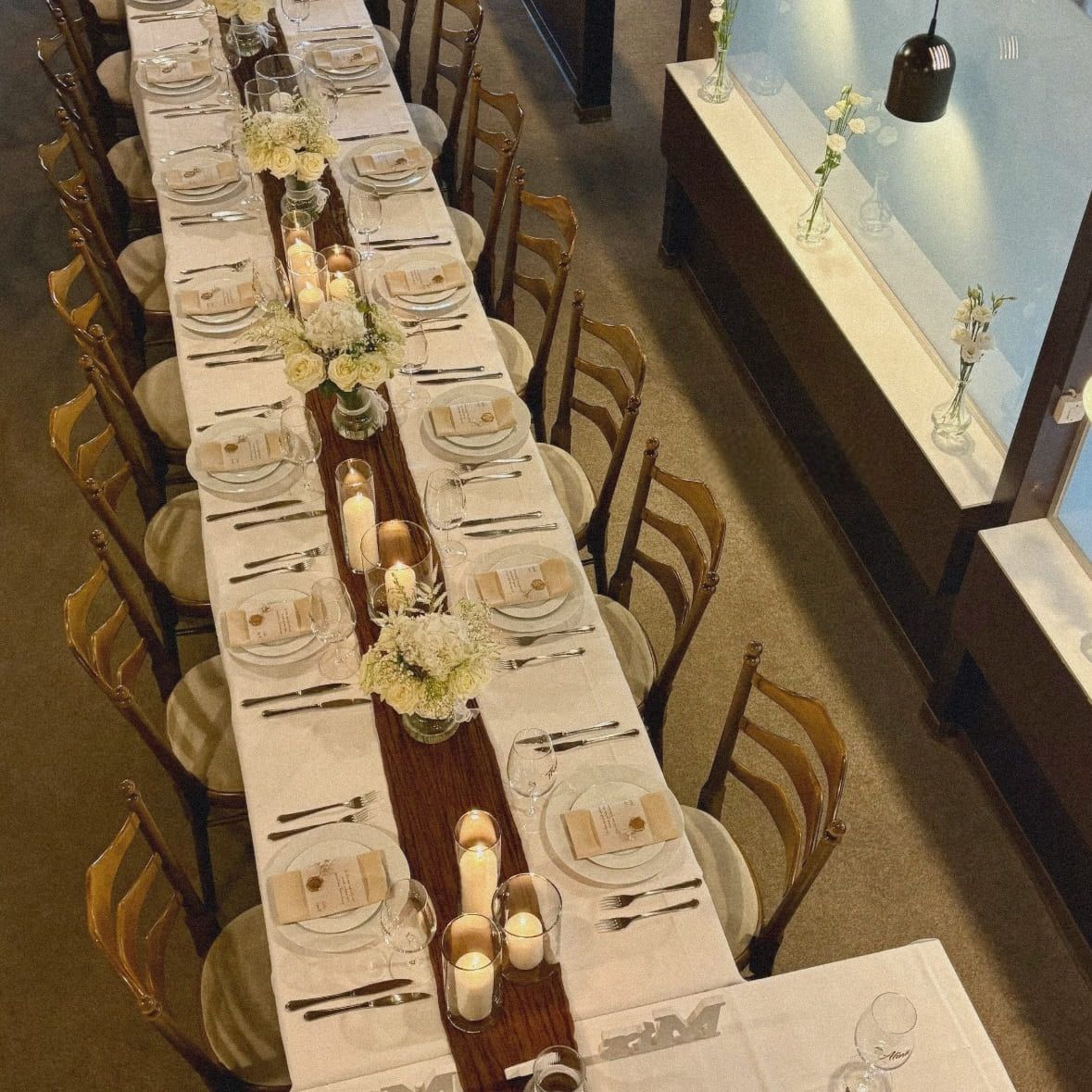 Festlich gedeckte lange Hochzeitstafel mit Kerzen und Blumenschmuck aus der Vogelperspektive