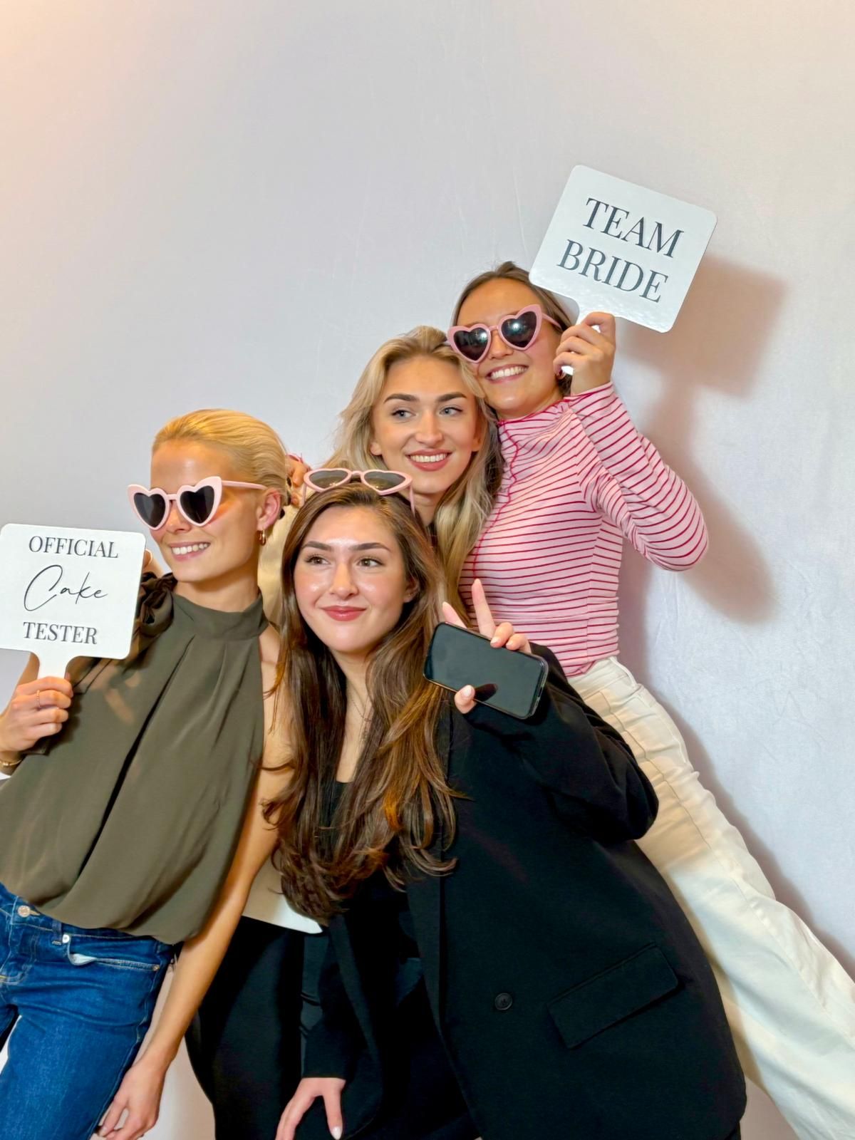 Freundinnen mit Team-Bride-Schildern vor Fotobox bei Hochzeit